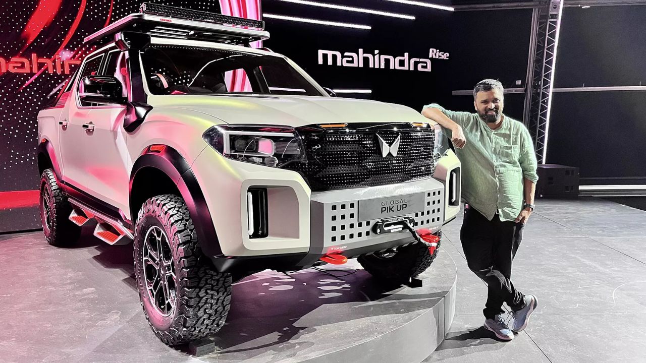 A image of silver colour Mahindra Thar EV which is palaced in mahindra showcase event with a man standing along the car
