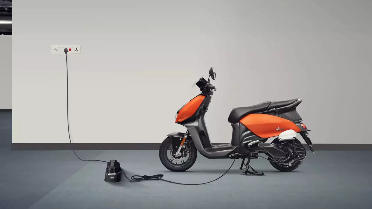 Here is a image of Electric scoter Vida V1 Plus in Orange and balack colour in a charging